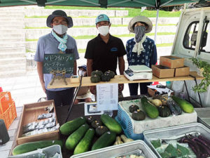 くさつファーマーズマーケットの主催者新喜多さんと、参加農家の河合雲平さんたちの軽トラック