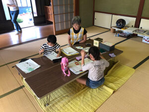 TERAコミュニティー鳥羽上「地域学童保育と集いの場」のようす画像　宿題をする1年生と中嶋さん