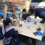 地球ハートビレッジ「地球を愛する衣食住DIY生きる学び塾」活動のようす　子どもたちが大人の指導を受けながら木製パズルを作成している　