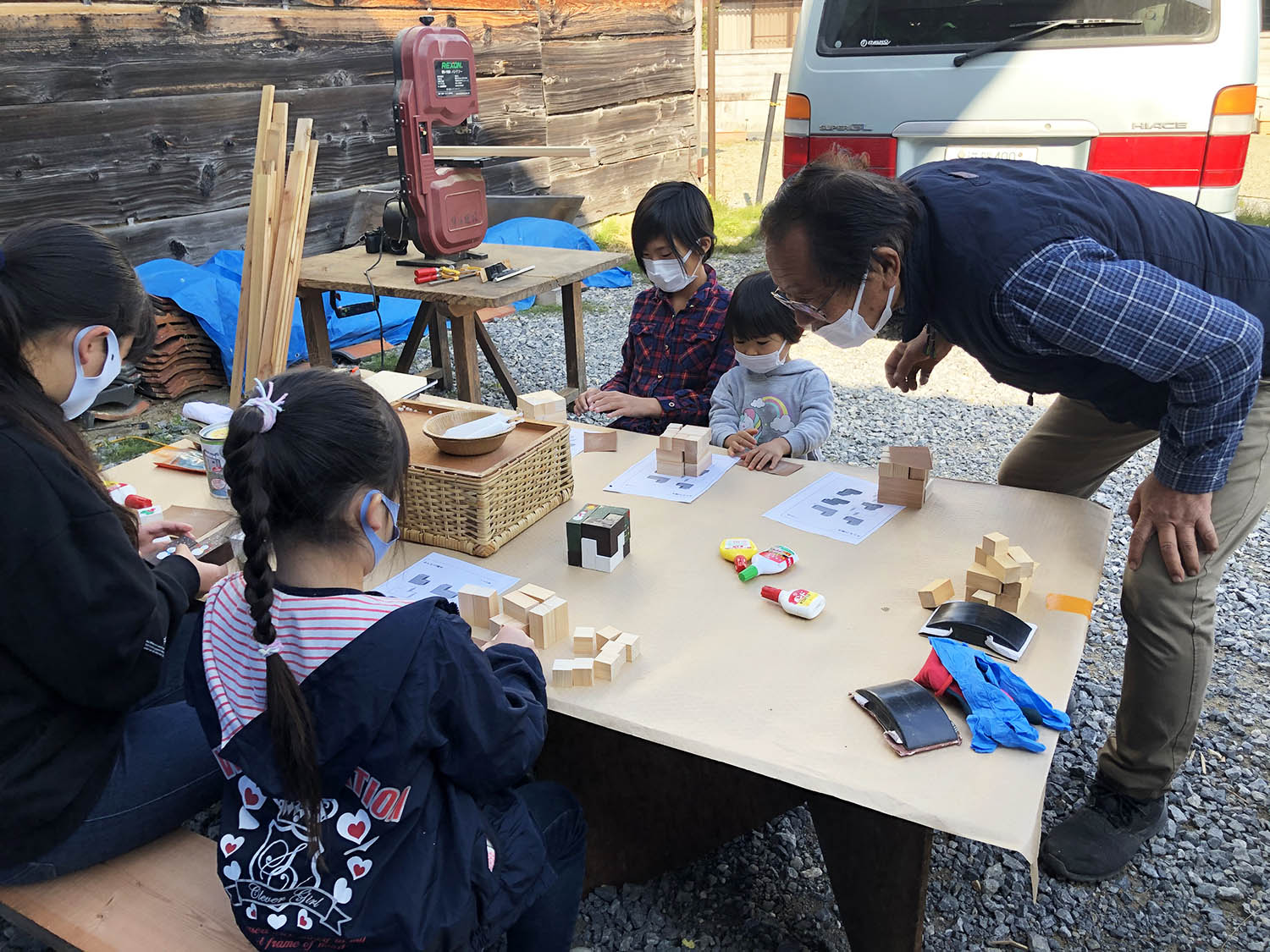 地球ハートビレッジ「地球を愛する衣食住DIY生きる学び塾」活動のようす　子どもたちが大人の指導を受けながら木製パズルを作成している　