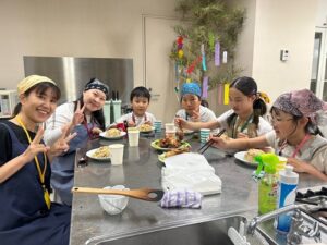 瀬田東国際交流クラブ　活動のようす画像　班ごとに食べる。ピースサインの大人たちと黙々と食べる子どもたち