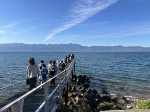 翔んでびわ湖の「大人のエコスクール」参加者の皆さんが、沖島を歩いてめぐる中で、びわ湖に突き出した桟橋まで出ていっているところ。