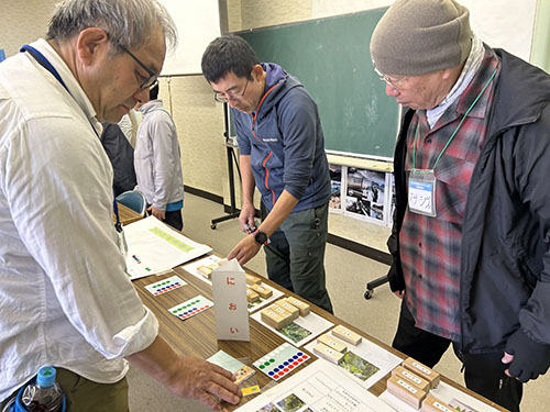 翔んでびわ湖の「大人のエコスクール」、やまのこの体験学習中。参加者とメンバーが、木片のにおいをかいでいるところ