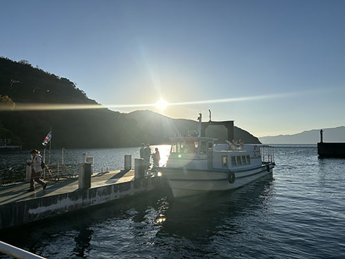 翔んでびわ湖の「大人のエコスクール」、堀切港にかえってきて桟橋に横付けされているチャーター船。夕陽が逆光になり、琵琶湖も輝いている。