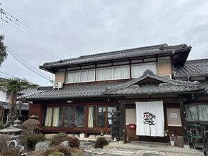 食養サークル　朝晴れ　活動のようす画像　「はなやの母屋（おもや）」の外観。普通の民家を改装された建物。玄関に大きな暖簾